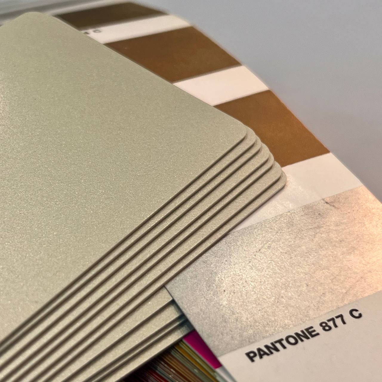 Серебряный пластик в массе рядом с веером Pantone Formula Guide. Подбор оттенка при производстве пластиковых карт в типографии МАДЖЕНТА