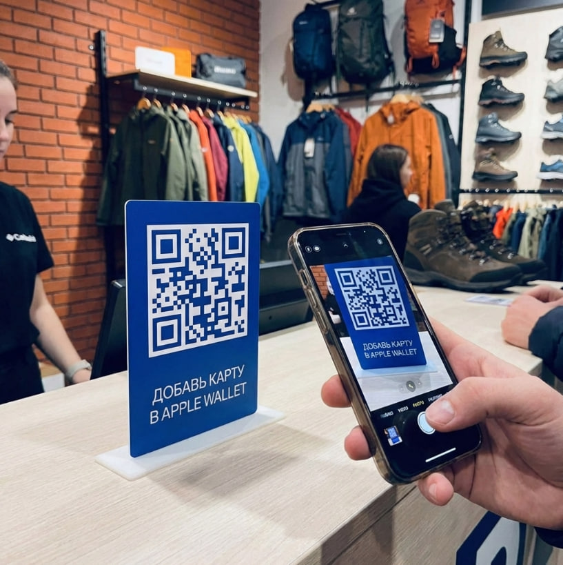 Пластиковая табличка на кассе магазина. Клиент магазина считывает QR-код